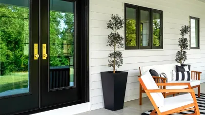Modern front porch featuring ProVia doors, stylish furniture, and lush greenery backdrop.