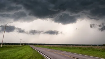 a road with grass and clouds above