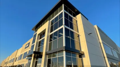 Modern commercial building with large glass windows under a clear blue sky during sunset.