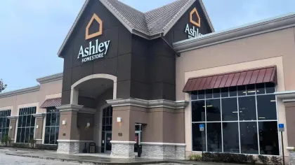 Exterior view of Ashley Homestore building under a cloudy sky with parking area in front.