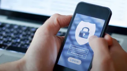 Hand holding smartphone with login screen and lock icon, laptop in background, LearningLab identity theft course text.