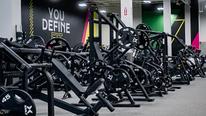 Modern gym with rows of black weight machines and motivational wall sign You Define Fit