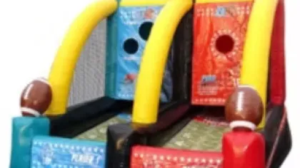 Inflatable football toss game with red and blue sides and football decorations for party fun.
