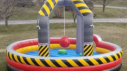 Inflatable outdoor game with circular base and hanging punching bag in red, yellow, black, and gray colors.