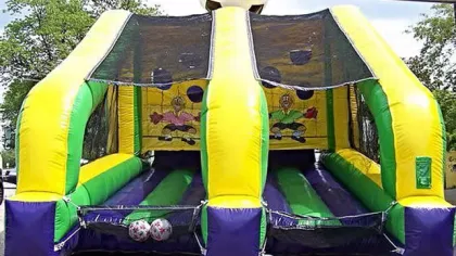 Inflatable soccer-themed game with two lanes and large soccer ball on top, bright yellow, green, and purple colors.
