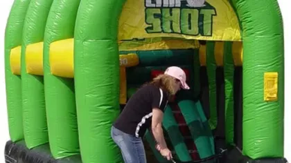 Woman playing golf chip shot game using inflatable green and yellow target with scoring zones.