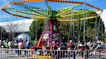 Colorful swing ride at an outdoor carnival with people enjoying seats on a sunny day