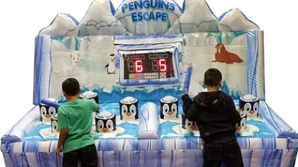 Two boys playing the Penguins Escape inflatable game with penguin targets and digital scoreboard