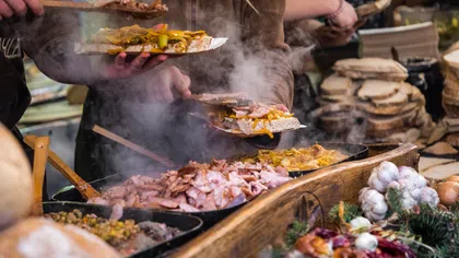 Steam rises from a food stall serving hot meat and vegetables on flatbreads at a market event.