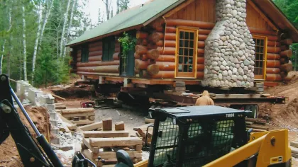 a log cabin with a tractor in front of it