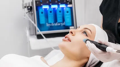 Woman receiving a modern facial treatment using a specialized skincare device in a spa clinic.