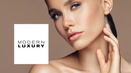 Close-up of a woman with clear skin and blue eyes posing beside modern luxury logo on beige background