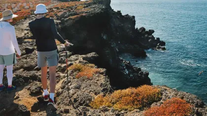 a couple of people on a cliff looking at a body of water