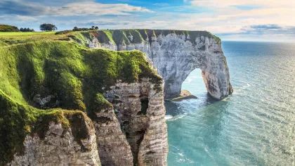 a cliff with a body of water below with Bempton Cliffs in the background