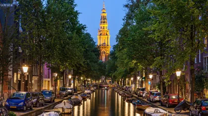a canal with cars and trees along it