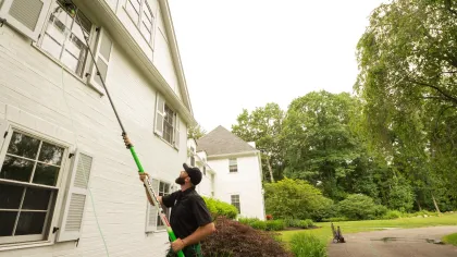a man holding a broom outside a house