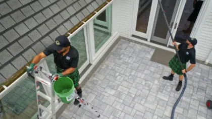 a few men cleaning the roof of a house