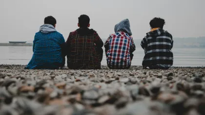 a group of people sitting on a beach looking at the water