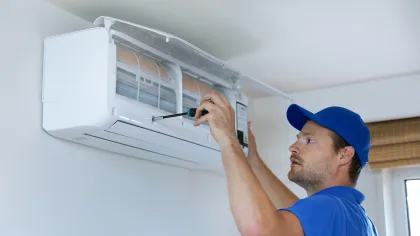 a man in a blue hat looking at a microwave