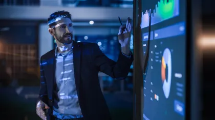 Businessman analyzing data and charts on a digital screen in a modern office at night.