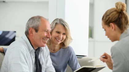 Happy mature couple consulting with female professional reviewing documents in modern office.