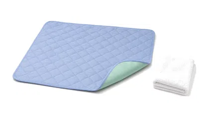 Blue quilted waterproof mat with folded white towel on white background for home or medical use