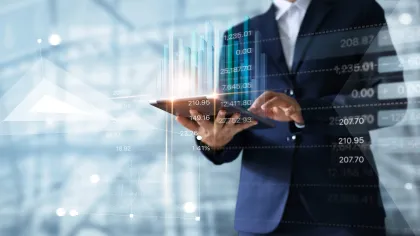 Business professional analyzing financial data on a tablet with abstract graphs in background.