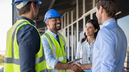 Construction professionals shaking hands, showcasing teamwork and collaboration on-site.