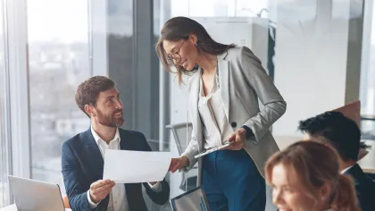 Professionals collaborating in a modern office, discussing charts and reports during a meeting.