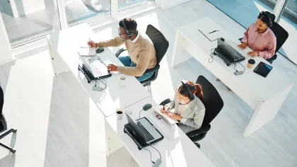 Three professionals working at desks in a bright, modern office space.