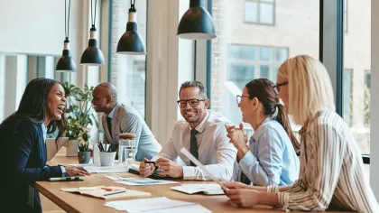 Diverse group of professionals collaborating around a large table in a modern office setting.