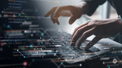 Close-up of hands typing on a laptop, overlaid with digital code and technology graphics.