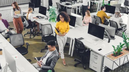 Modern office environment featuring diverse professionals collaborating at desks with plants.