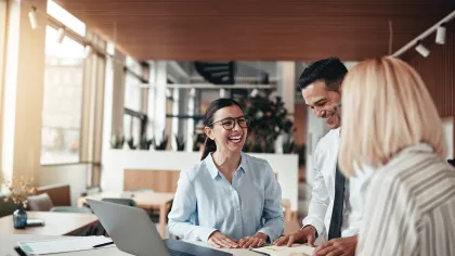 Three professionals in an office discussing ideas and collaborating, showcasing teamwork and positivity.