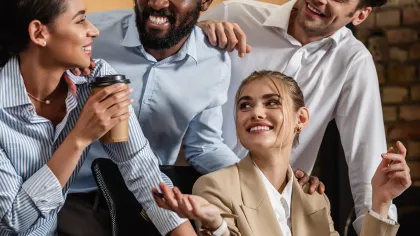 Four colleagues enjoying a light moment in a modern office setting, showcasing teamwork and camaraderie.