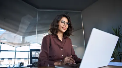 Professional woman working on laptop in modern office environment, focused and engaged in her task.