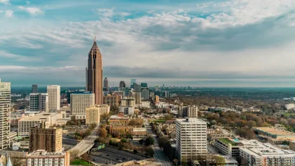 Aerial view of Atlanta skyline with tall buildings under a partly cloudy sky during daytime.