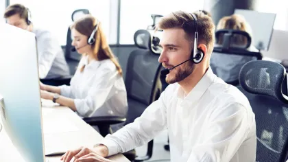 a man wearing headphones and sitting at a desk with a laptop