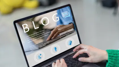 Person typing on laptop displaying a blog interface with icons and text on screen.
