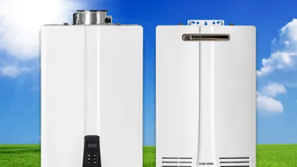 Two white tankless water heaters standing on green grass under a bright sun and blue sky with clouds.