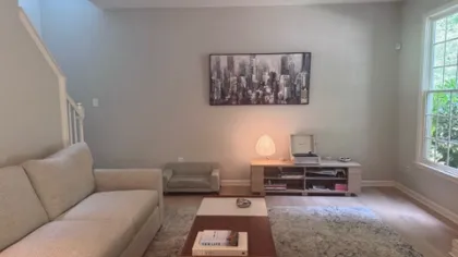 Cozy living room with beige sofa, modern coffee table, large window, and cityscape wall art in soft lighting.