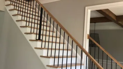 Modern indoor staircase with wooden steps and black metal railings against beige walls in a residential home.
