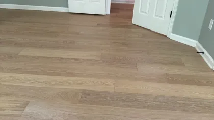 Light wood laminate flooring in a room with two white doors and gray walls.