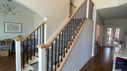 Indoor staircase with wooden handrails and black balusters in a modern home with hardwood floors.