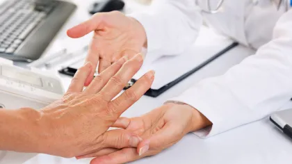 Doctor checking patient's pulse by holding their wrist during a medical consultation at a clinic.