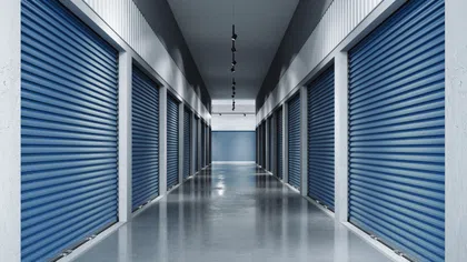 Long corridor with closed blue rolling storage unit doors on both sides and polished concrete floor