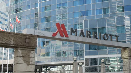 Entrance sign of Marriott hotel with modern glass building and flags including Canada and USA in the background