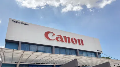 Canon office building with large red logo under blue sky and white clouds
