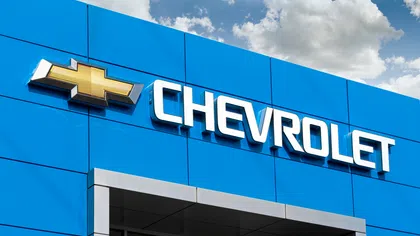 Chevrolet dealership sign on blue building exterior under partly cloudy sky.