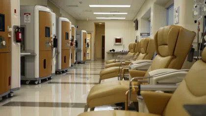 Empty medical infusion chairs and dialysis machines in a clean treatment center with bright lighting.